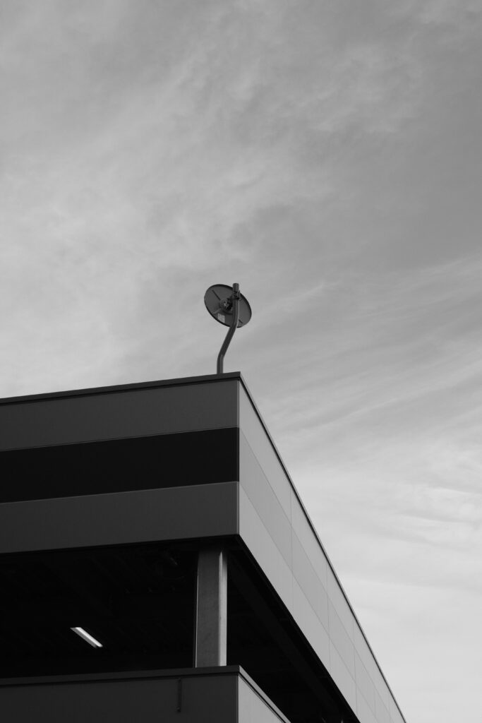 A striking black and white image featuring a modern building with a satellite dish against a sky backdrop.